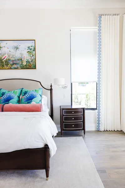 Infused with vibrant colors and tropical accents, this bedroom captures the essence of relaxation. The understated furnishings allow the artwork and textiles to shine.