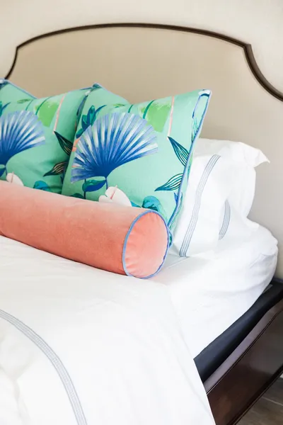 This close-up highlights the vivid floral and botanical patterns of the bedding, bringing a lively pop of color to the serene bedroom setting.