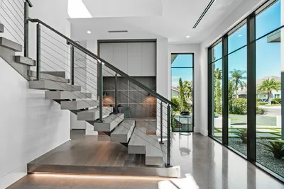 The staircase is a striking feature within the home, blending functionality and style. Its modern railing complements the surrounding natural light, creating an inviting and visually impressive entryway.