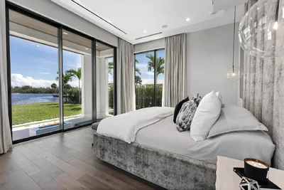 Emphasizing connectivity with the outdoors, this bedroom features expansive windows providing picturesque views of the lake, infusing the space with light and a sense of openness.