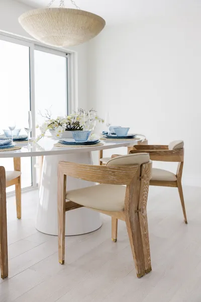 The dining area showcases minimalist elegance with light wood furniture and subtle coastal decor, offering a perfect space for intimate gatherings bathed in natural light.